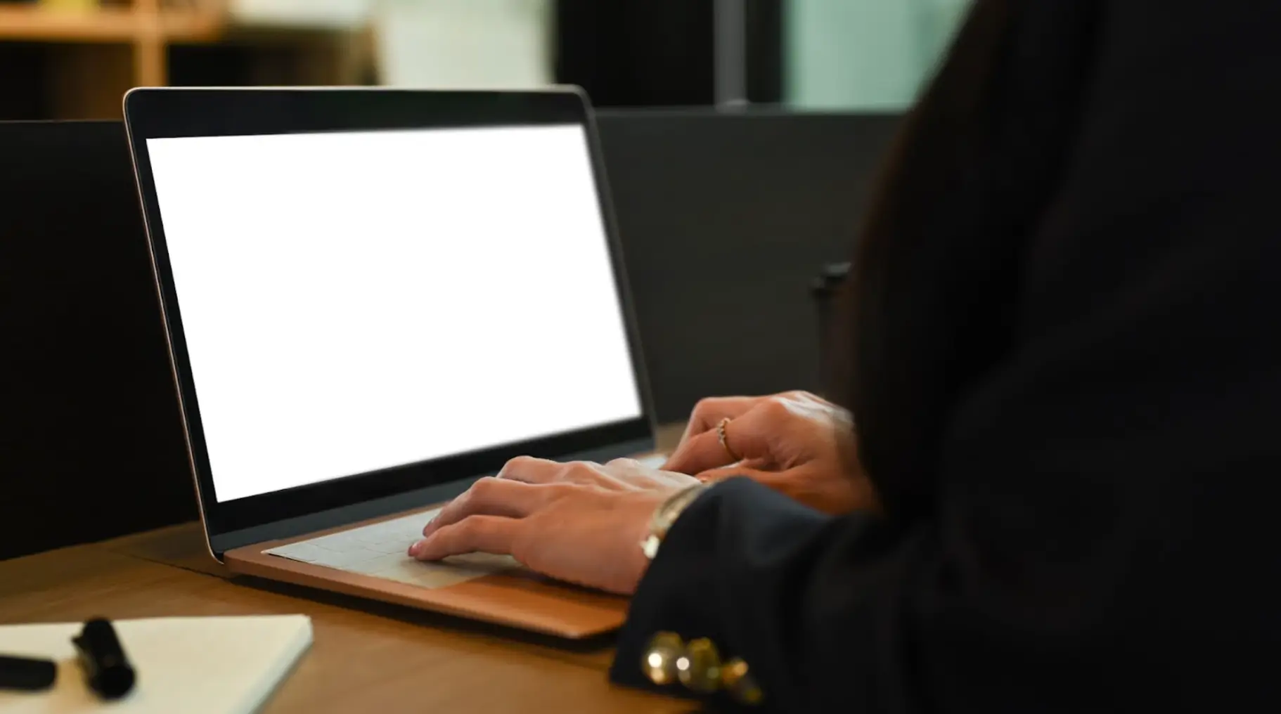 Person typing on a laptop with a blank white screen, representing the start of building strong real estate email marketing ideas.