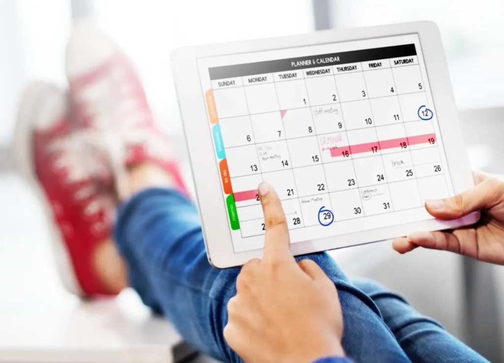 Person checking appointments on a digital calendar while planning campaigns for real estate email marketing services.