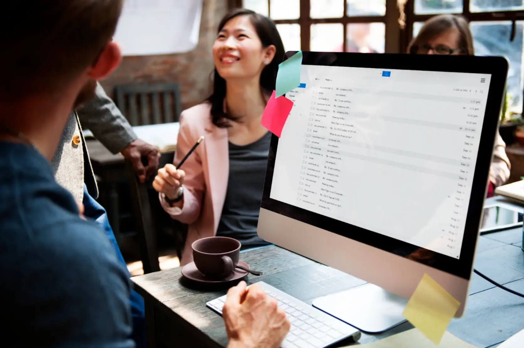 Team collaborating in the office with a computer screen showing emails related to real estate email marketing services.