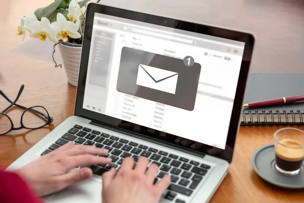 Real estate business concept with agents working on documents and laptop, miniature house model, and house keys on desk which illustrates email marketing for real estate business.